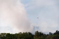 Helicopter firefighter flying over smoke column in forest fire Royalty Free Stock Photo