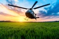 A helicopter flying over a green field at sunset Royalty Free Stock Photo