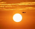 Helicopter silhouette with vibrant sunset sky.