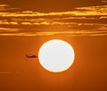 Helicopter silhouette on vibrant sunset sky.