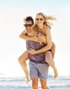 Hell carry her through. a man piggybacking his girlfriend on the beach. Royalty Free Stock Photo