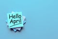 Hello April greeting written on blue paper stack at desk with empty space for text, mockup or template Royalty Free Stock Photo