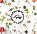 HELLO APRIL lettering surrounded with pink flowers, petals and figs isolated on white