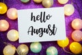 Hello August text on paper card top view on purple bokeh background