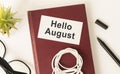 Hello August - text on a sticky note against rustic wood with