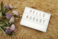 Hello August word in light box and flower bouquet