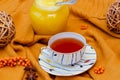Hello Autumn background. Bright yellow wool sweater, cup of tea, honey, decorative vine balls and sea buckthorn berries
