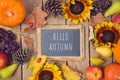 Hello autumn concept with chalkboard,  pumpkin, apples and sunflowers on wooden table. Thanksgiving holiday background. Top view Royalty Free Stock Photo