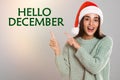 Hello December greeting card. Happy woman in Santa hat on light background Royalty Free Stock Photo