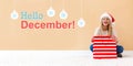 Hello December message with woman with Santa hat holding a shopping bag Royalty Free Stock Photo