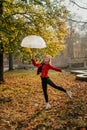 Hello fall, autumn season, fall mood, positive emotions. Teenager girl jumping with transparent umbrella and enjoying