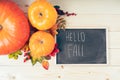 Hello fall. Pumpkins, berries and fallen leaves with chalk blackboard frame on wooden background. Halloween, Thanksgiving day or