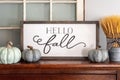 Hello fall sign and neutral colored pumpkins on wood mantel