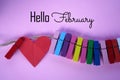 Hello February. Welcoming month of February card and greeting concept with colorful wooden paper clips and red heart - love sign Royalty Free Stock Photo