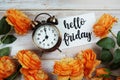 Hello Friday card and alarm clock with orange flower decoration on wooden background Royalty Free Stock Photo