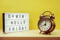 Hello Friday text in light box with alarm clock on yellow background