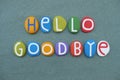 Hello Goodbye, creative greet composed with multi colored stone letters over green sand Royalty Free Stock Photo