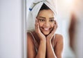 Hello gorgeous. an attractive young woman looking at her face in the bathroom mirror.