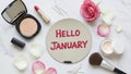Hello January message on mirror with makeup products and rose petals Royalty Free Stock Photo