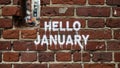 Hello January message spray painted on a rustic red brick wall symbolizing new beginnings and the start of a fresh year Royalty Free Stock Photo