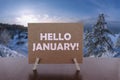 Hello January text on card on the table with sunny winter landscape background