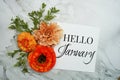 Hello January text with orange flower bouquet on marble background