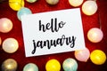 Hello January text on paper card top view on red bokeh background