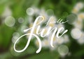 Hello June hand drawn lettering design isolated on a blurred floral background. Royalty Free Stock Photo