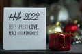 Hello 2022. Let`s spread love, peace and kindness. New Year inspirational text message on a notepaper and red Christmas gift box
