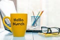 Hello march - inscription on yellow morning cup of coffee or tea at business office background. Spring time concept Royalty Free Stock Photo