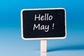 Hello May - inscription about last spring month beginning at litle wooden tag at blue background