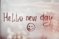 Hello new day message written finger with smile on foggy glass wet window