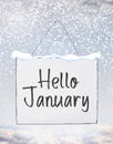 Hello January text on white plate board banner with cold snow fl