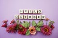 Hello October alphabet letters with pink flower decoration on purple background