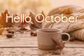 Hello October card. Cup of hot drink and autumn leaves on table