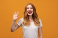 Portrait of friendly woman with wavy redhead, standing waving hand, looking at camera with engaging toothy smile Royalty Free Stock Photo