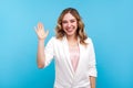 Hello! Portrait of friendly kind cheerful girl waving hand saying hi welcome, smiling. isolated on blue background