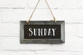 Hello sunday text on hanging board white brick outdoor wall Royalty Free Stock Photo