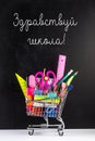 Hello school! Shopping cart with school supplies over chalkboard background Royalty Free Stock Photo