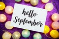 Hello September text on paper card top view on purple bokeh background Royalty Free Stock Photo