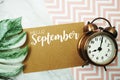 Hello September typography text on paper card with alarm clock and Monstera leave Royalty Free Stock Photo