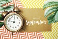 Hello September typography text on paper card with alarm clock and Monstera leave Royalty Free Stock Photo