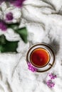 Hello spring. Black tea in a cup with a small bouquet of lilac flowers on the side on a white woolen blanket bed at home Royalty Free Stock Photo