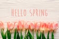 hello spring text sign, beautiful pink tulips on white rustic wooden background flat lay. flowers in soft morning sunlight with s Royalty Free Stock Photo