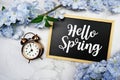 Hello Spring text on wooden blackboard and flower decoration on marble background