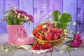 Hello summer concept. Ripe strawberries in a basket, a bouquet of wild flowers in a pink shoe