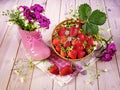 Hello summer concept. Ripe strawberries in a basket, a bouquet of wild flowers in a pink shoe