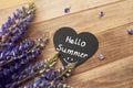 hello summer lettering with smile on black wooden heart with fresh lupine flowers on old brown wooden table