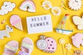 Hello summer text on lightbox and cute summer symbols on yellow background. Top view, Flat lay. Creative summer concept