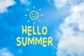 Hello summer text written against blue sky with clouds with a sun symbol Royalty Free Stock Photo